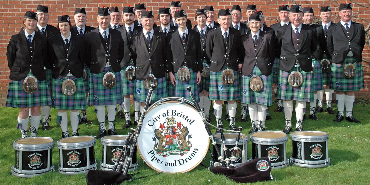 Pipe band wearing tartan kilts and black doublets